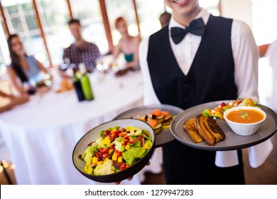 Mid Section Of Waitress Holding Food On Plate In Restaurant