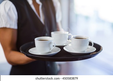 Mid Section Of Waitress Holding A Tray Of Coffee Cups In Restaurant