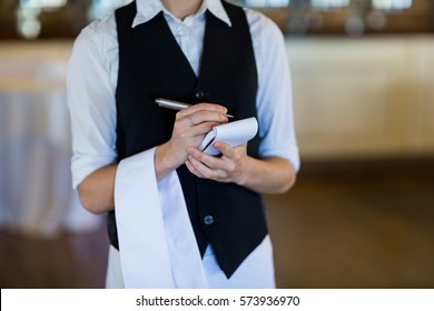 Mid section of waitress taking order in restaurant