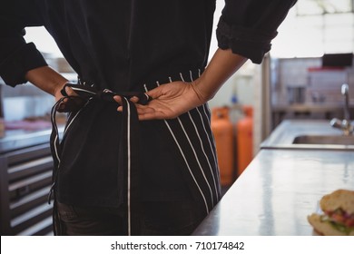 Mid section of waitress wearing apron at cafe - Powered by Shutterstock