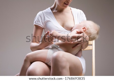 Mid section of woman breastfeeding baby boy (1-2) studio shot