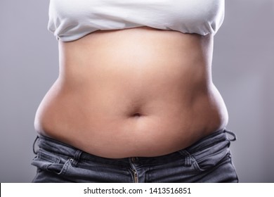 Mid Section Of A Woman With Excessive Belly Fat Against Grey Background