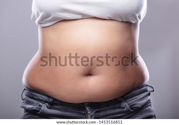 Mid Section Of A Woman With Excessive Belly\
Fat Against Grey Background