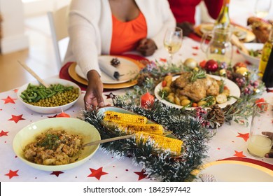 Mid Section Of Woman Picking Up A Food Plate While Sitting And Having Lunch On Dining Table In The Living Room At Home. Christmas Festivity Tradition Celebration Concept