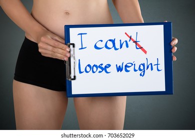 Mid Section Of A Woman Showing Message I Can't Lose Weight On Clipboard