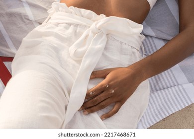 Mid Section Of Woman Wearing Linen Pants Laying On The Beach Towel