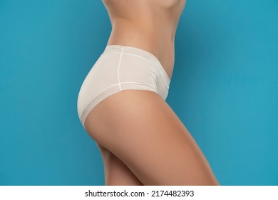 Mid Section Of Woman Wearing White Briefs, Side View On A Blue Background.