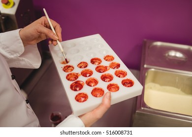 Mid section of worker painting a chocolate mould using colored chocolate in kitchen - Powered by Shutterstock