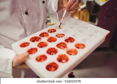 Mid section of worker painting a chocolate mould using colored chocolate in kitchen - Powered by Shutterstock