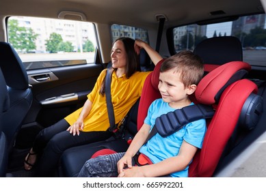 Mid shot of a mother and her son in the automobile; sitting on back seats, buckled up, smiling people