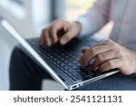 A mid-adult cheerful Caucasian male entrepreneur engaged in using his laptop while seated outside, sporting professional attire.