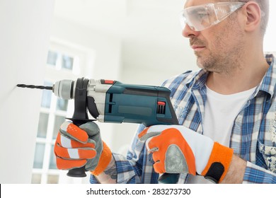 Mid-adult Man Drilling Hole In Wall