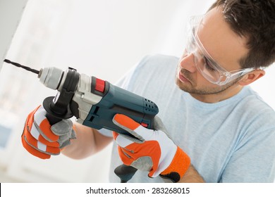 Mid-adult Man Drilling In Wall