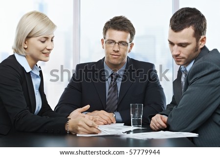 Mid-adult professionals at businessmeeting, looking at documents deep in discussion.?