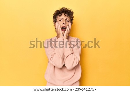 Mid-aged caucasian woman on vibrant yellow whining and crying disconsolately.