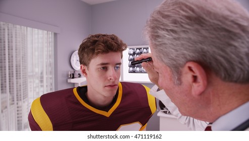 Mid-aged Doctor Examining Football Player After Concussion.