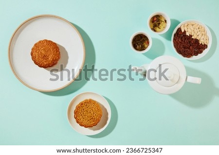 Mid-Autumn Festival concept of a tea set displayed with a dish of pumpkin seeds and melon seeds. Baked mooncakes featured. id-Autumn Festival is one of the most important traditional days