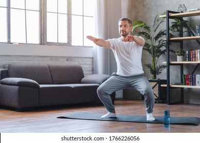 Middle Adult Man Doing Squats And Exercising In Living Room At Home