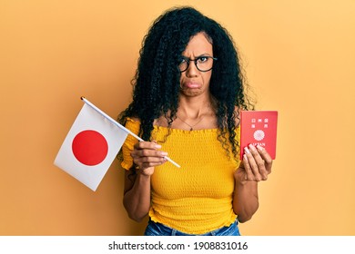 Middle Age African American Woman Holding Japan Flag And Passport Depressed And Worry For Distress, Crying Angry And Afraid. Sad Expression. 