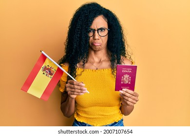 Middle Age African American Woman Holding Spain Flag And Passport Depressed And Worry For Distress, Crying Angry And Afraid. Sad Expression. 