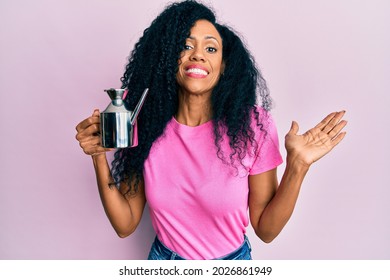 Middle Age African American Woman Holding Olive Oil Can Celebrating Achievement With Happy Smile And Winner Expression With Raised Hand 