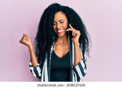 Middle Age African American Woman Having Conversation Talking On The Smartphone Screaming Proud, Celebrating Victory And Success Very Excited With Raised Arm 