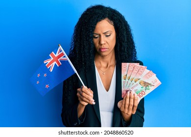 Middle Age African American Woman Holding New Zealand Flag And Dollars Depressed And Worry For Distress, Crying Angry And Afraid. Sad Expression. 