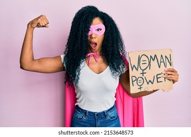 Middle Age African American Woman Wearing Super Hero Costume Holding Woman Power Banner Afraid And Shocked With Surprise And Amazed Expression, Fear And Excited Face. 