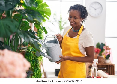 Middle age african american woman florist smiling confident watering plant at flower shop - Powered by Shutterstock