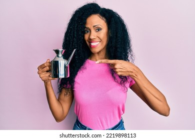 Middle Age African American Woman Holding Olive Oil Can Smiling Happy Pointing With Hand And Finger 