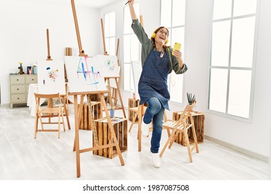 Middle Age Artist Woman Smiling Happy And Dancing Painting At Art Studio.