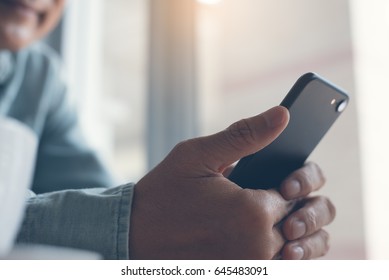 Middle Age Asian People,  30-40s Casual Man Checking Internet Application On Smartphone. Smiling Man Using Mobile Smart Phone At Home Interior, Close Up.