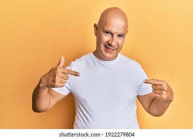 Middle Age Bald Man Wearing Casual White Tshirt Looking Confident With Smile On Face, Pointing Oneself With Fingers Proud And Happy. 