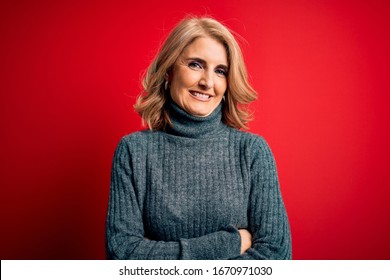 Middle Age Beautiful Blonde Woman Wearing Casual Turtleneck Sweater Over Red Background Happy Face Smiling With Crossed Arms Looking At The Camera. Positive Person.