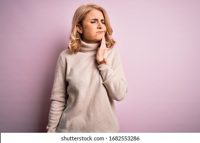 Middle age beautiful blonde woman wearing casual turtleneck sweater over pink background touching mouth with hand with painful expression because of toothache or dental illness on teeth. Dentist