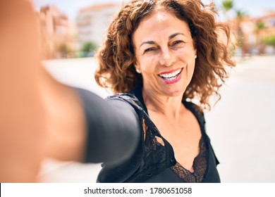 Middle age beautiful brunette woman smiling happy and confident. Standing with smile on face make selfie by camera on the town street - Powered by Shutterstock