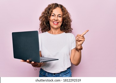 Middle age beautiful business woman working using laptop over isolated pink background smiling happy pointing with hand and finger to the side