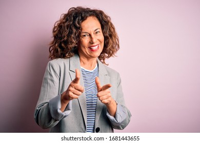 Middle age beautiful businesswoman wearing elegant jacket over isolated pink background pointing fingers to camera with happy and funny face. Good energy and vibes.