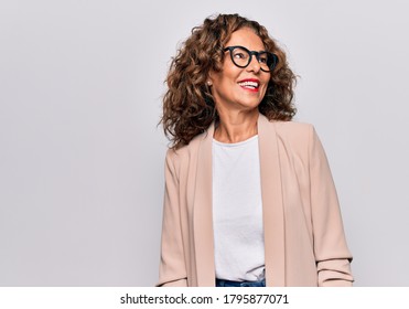 Schöne Geschäftsfrau im Mittelalter, die eine Brille trägt, die auf isoliertem, weißem Hintergrund steht und nach der Seite schaut, sich die Prospektposition mit natürlichem Gesicht entspannen und selbstbewusstes Lächeln genießen kann.