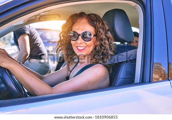 Middle age beautiful couple on vacation\
wearing sunglasses smiling happy driving\
car.