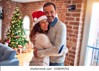 Middle age beautiful couple smiling happy and confident. Standing and hugging around christmas tree at home - Powered by Shutterstock