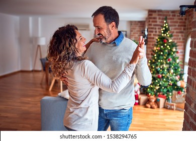 Middle age beautiful couple smiling happy and confident. Standing and dancing around christmas tree at home - Powered by Shutterstock