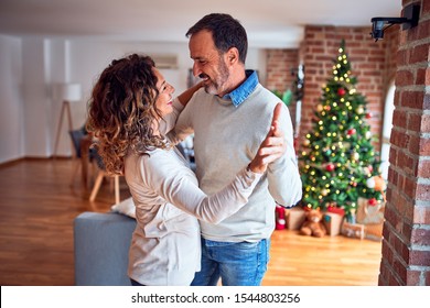 Middle age beautiful couple smiling happy and confident. Standing and dancing around christmas tree at home - Powered by Shutterstock