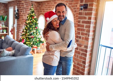 Middle age beautiful couple smiling happy and confident. Standing and hugging around christmas tree at home - Powered by Shutterstock