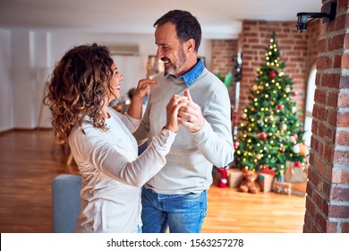 Middle age beautiful couple smiling happy and confident. Standing and dancing around christmas tree at home - Powered by Shutterstock