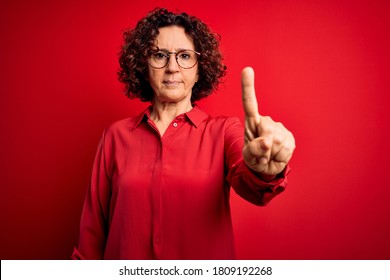 Middle Age Beautiful Curly Hair Woman Wearing Casual Shirt And Glasses Over Red Background Pointing With Finger Up And Angry Expression, Showing No Gesture