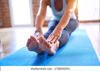 Middle Age Beautiful Sportwoman Sitting On Mat Practicing Yoga Doing Seated Forward Fold Pose At Gym