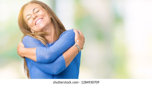 Middle age beautiful woman wearing winter sweater over isolated background Hugging oneself happy and positive, smiling confident. Self love and self care