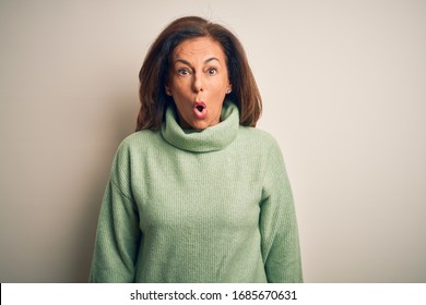 Middle age beautiful woman wearing casual turtleneck sweater over isolated white background afraid and shocked with surprise expression, fear and excited face.