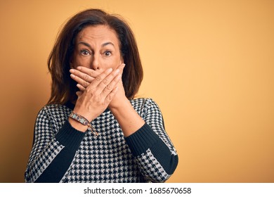 Middle age beautiful woman wearing casual sweater over isolated yellow background shocked covering mouth with hands for mistake. Secret concept. - Shutterstock ID 1685670658